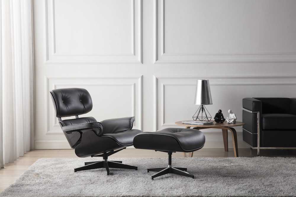 fauteuil lounge eames et ottoman eams design en cuir noir et bois de frêne noir avec une base en alu poli chromé dans un salon