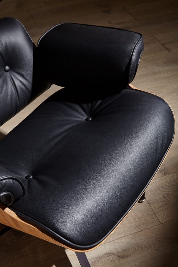 assise copie fauteuil charles eames avec ottoman cuir pleine fleur noir bois de frêne base alu noir dans un salon